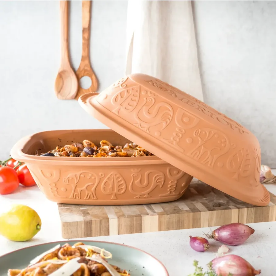 Stomende terracotta Römertopf op een houten keukentafel